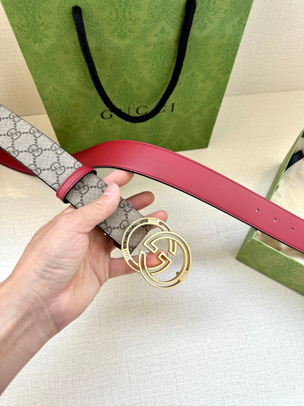 Gucci belt close-up of buckle: gray GG monogram strap with red leather strap section