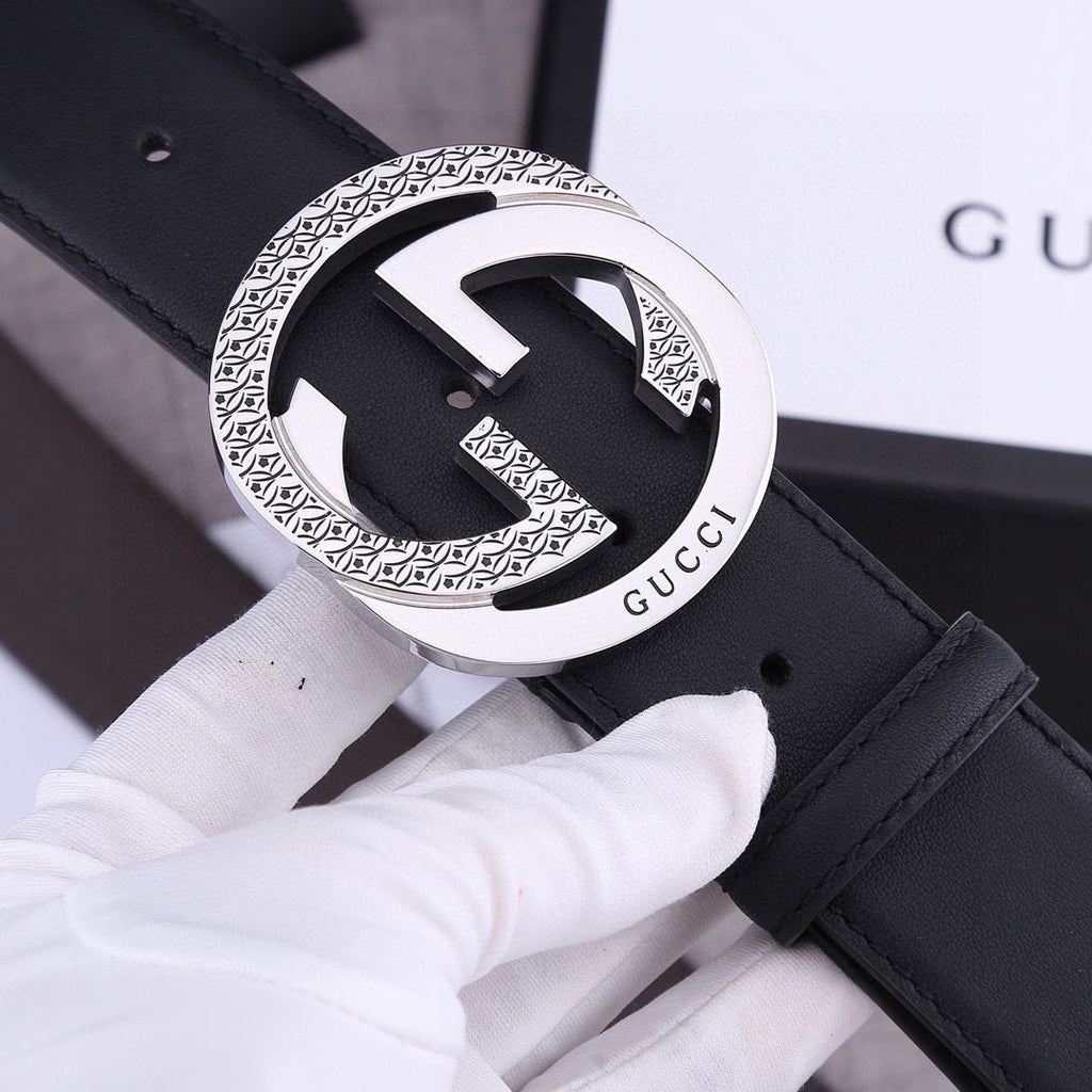 Black leather belt with silver-toned GG-style buckle, patterned edge detailing