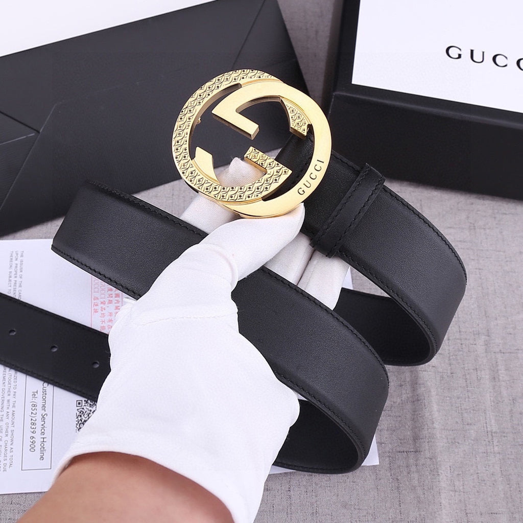 Black leather belt with gold GG-style buckle close-up and stitched strap edge