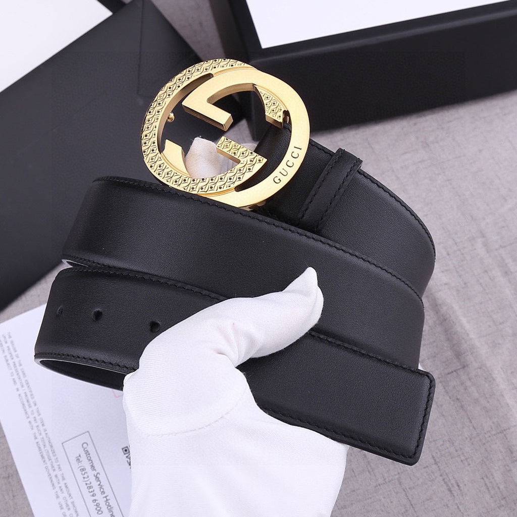 Black leather belt with gold GG-style round buckle and embossed signature detail