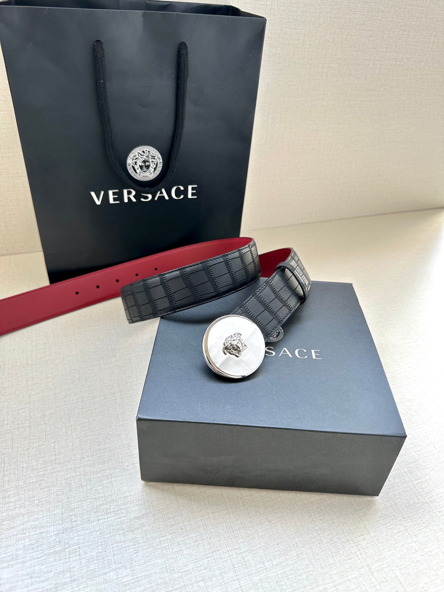 Versace belt with black grid strap, round medallion buckle, red underside
