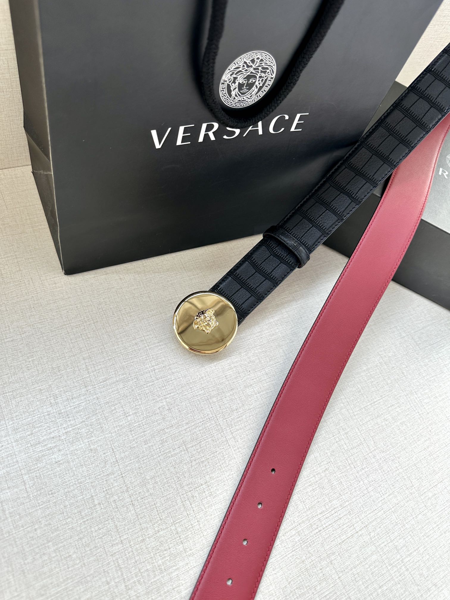 Versace belt with black grid strap and gold medallion buckle, red leather strap end