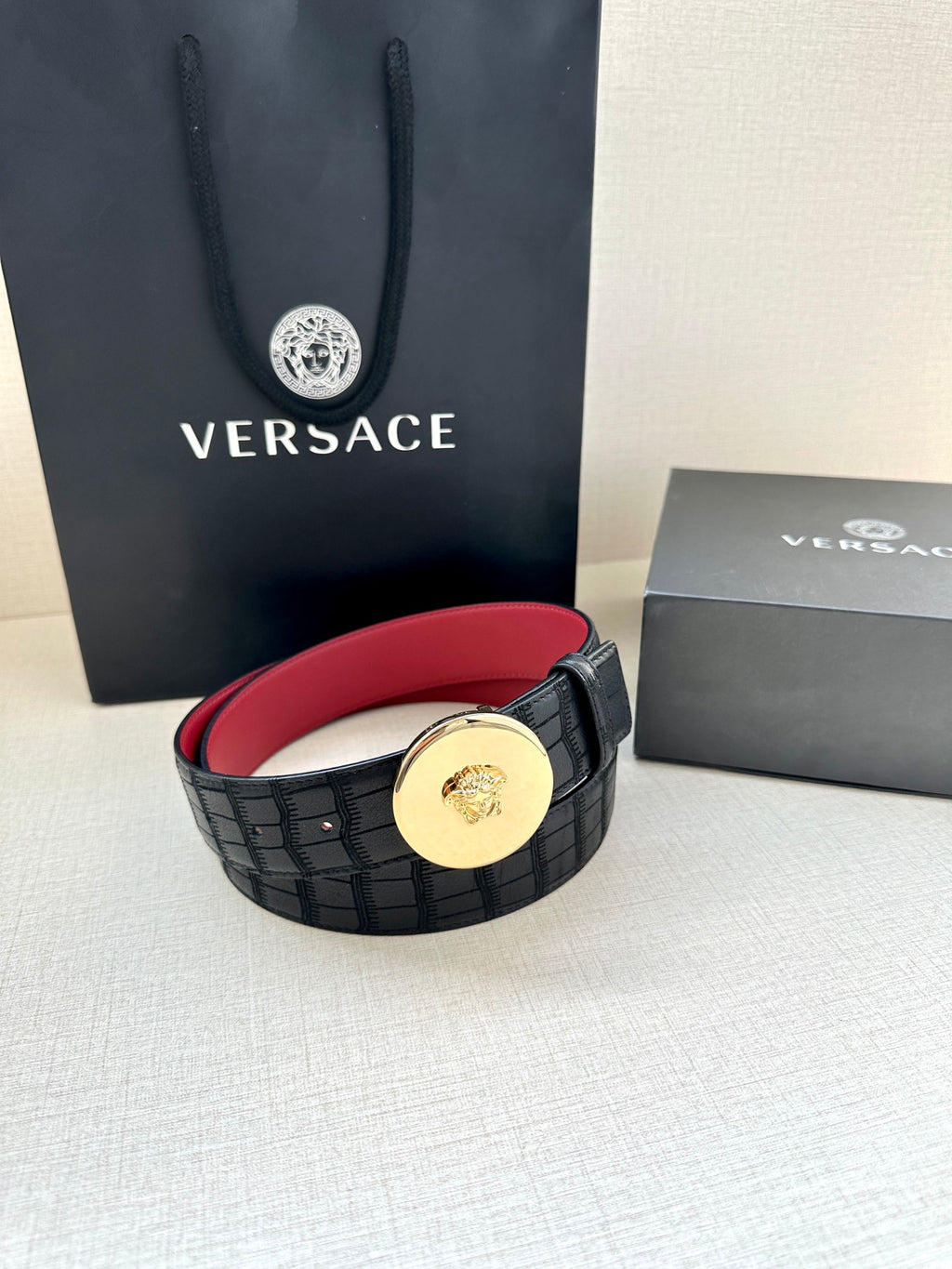 Versace belt with black grid strap and gold medallion buckle, red inner lining