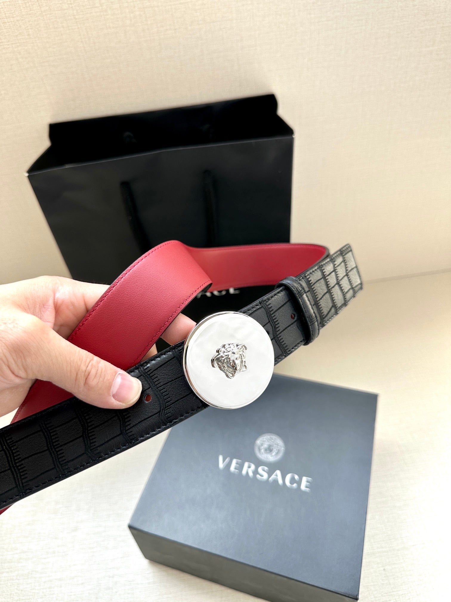Versace belt with black grid-pattern strap and red leather backing, round logo buckle