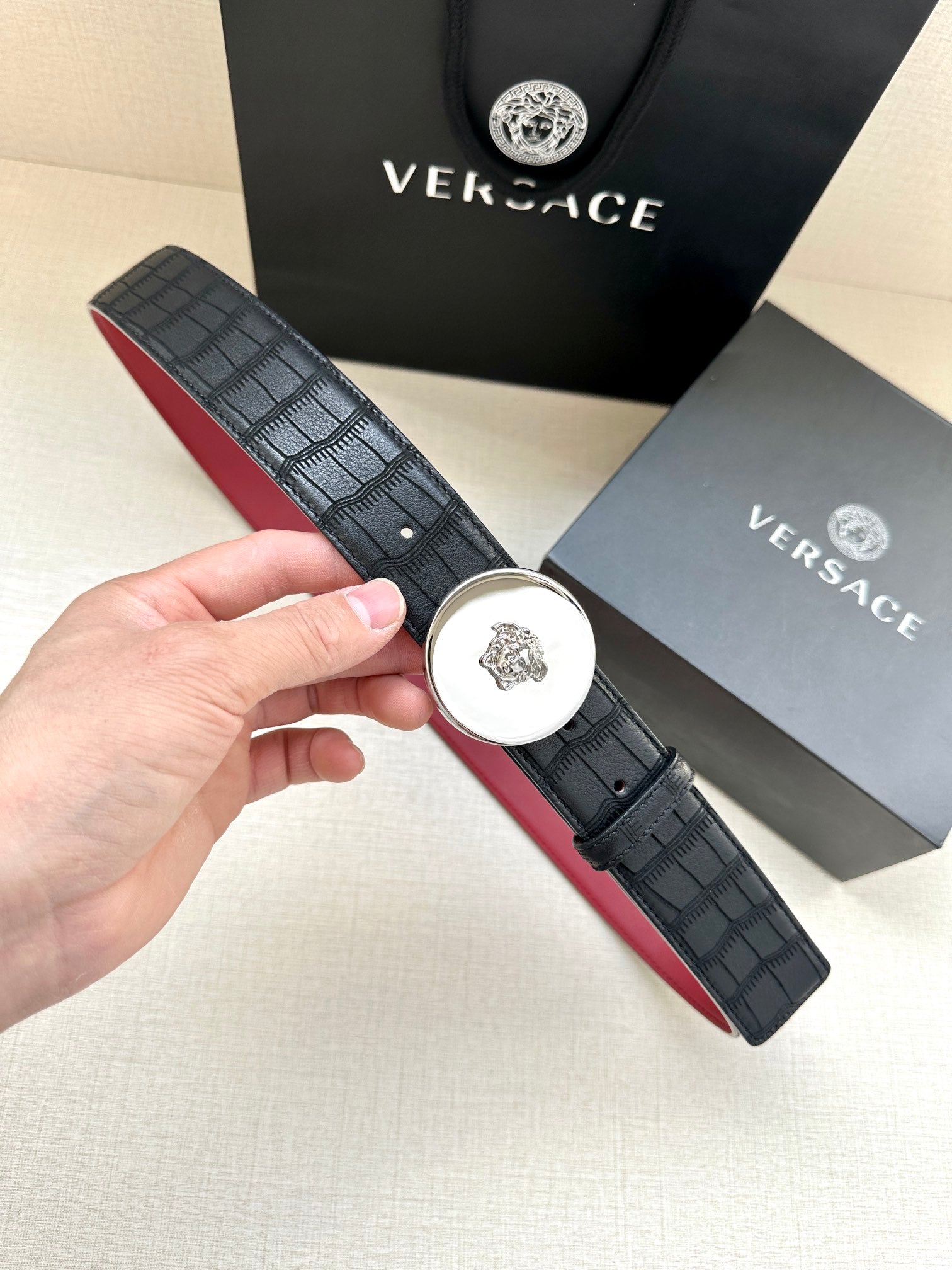 Versace belt with black textured strap and round medallion buckle, gold-tone center