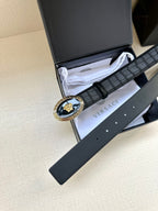 Black embossed leather belt with gold oval medallion buckle and exposed pin holes