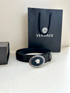 Black leather belt with embossed pattern and gold oval medallion buckle
