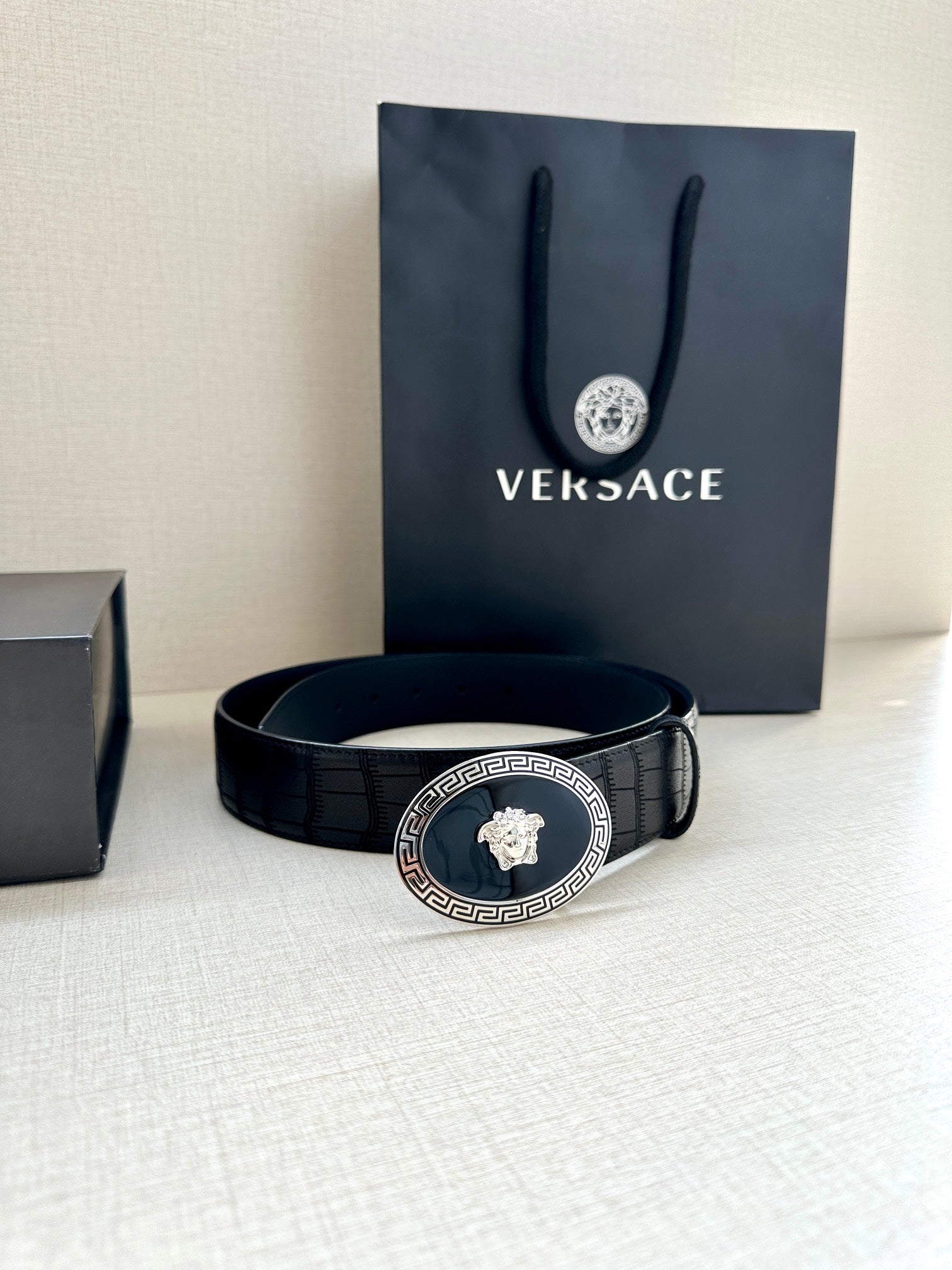 Black leather belt with embossed pattern and gold oval medallion buckle