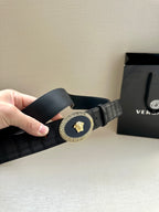 Black leather belt with embossed texture and gold oval buckle, angled view