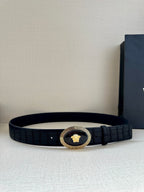 Black embossed leather belt with gold oval medallion buckle and single prong