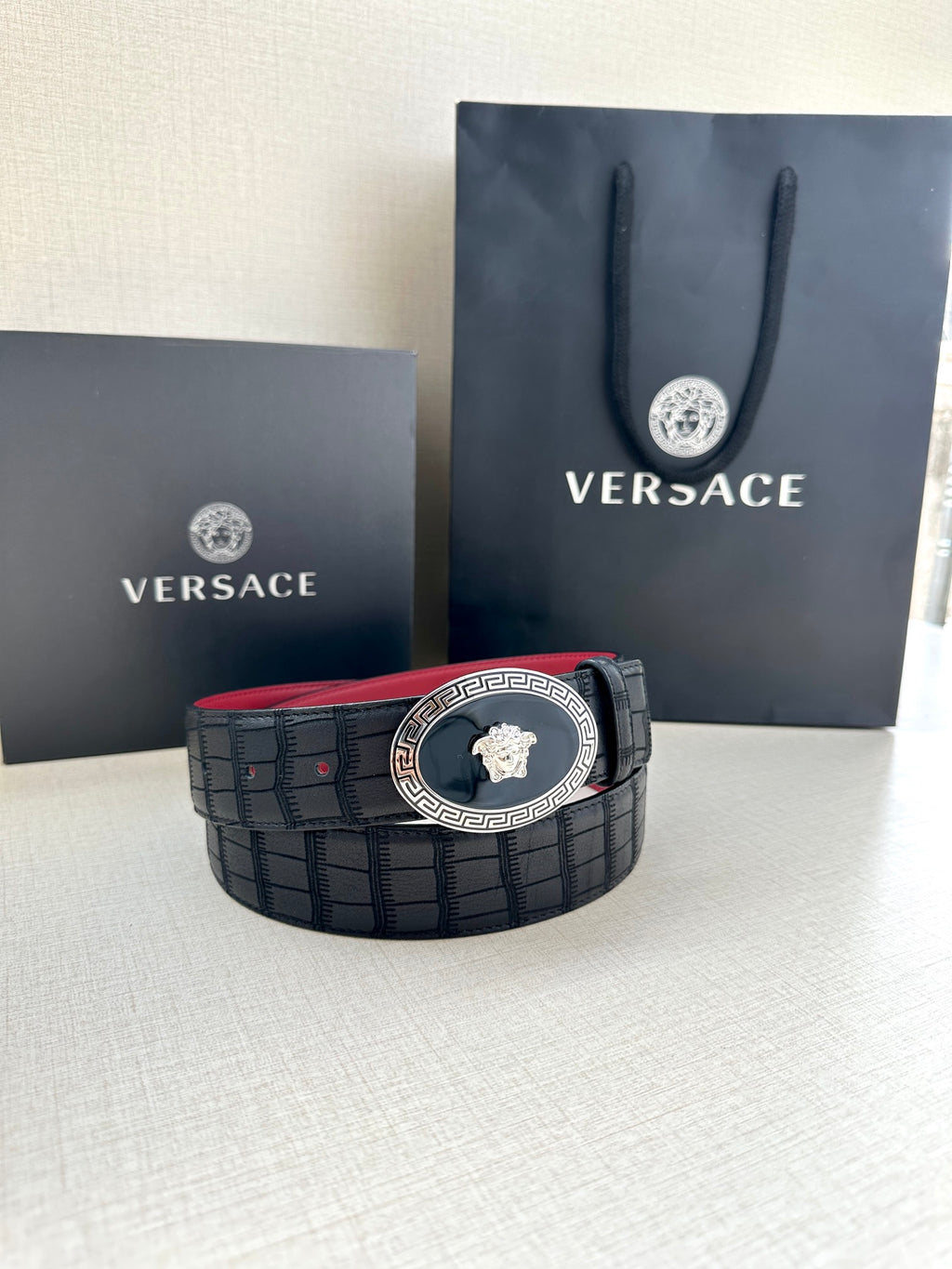 Versace belt on display: black textured strap with round gold medallion buckle