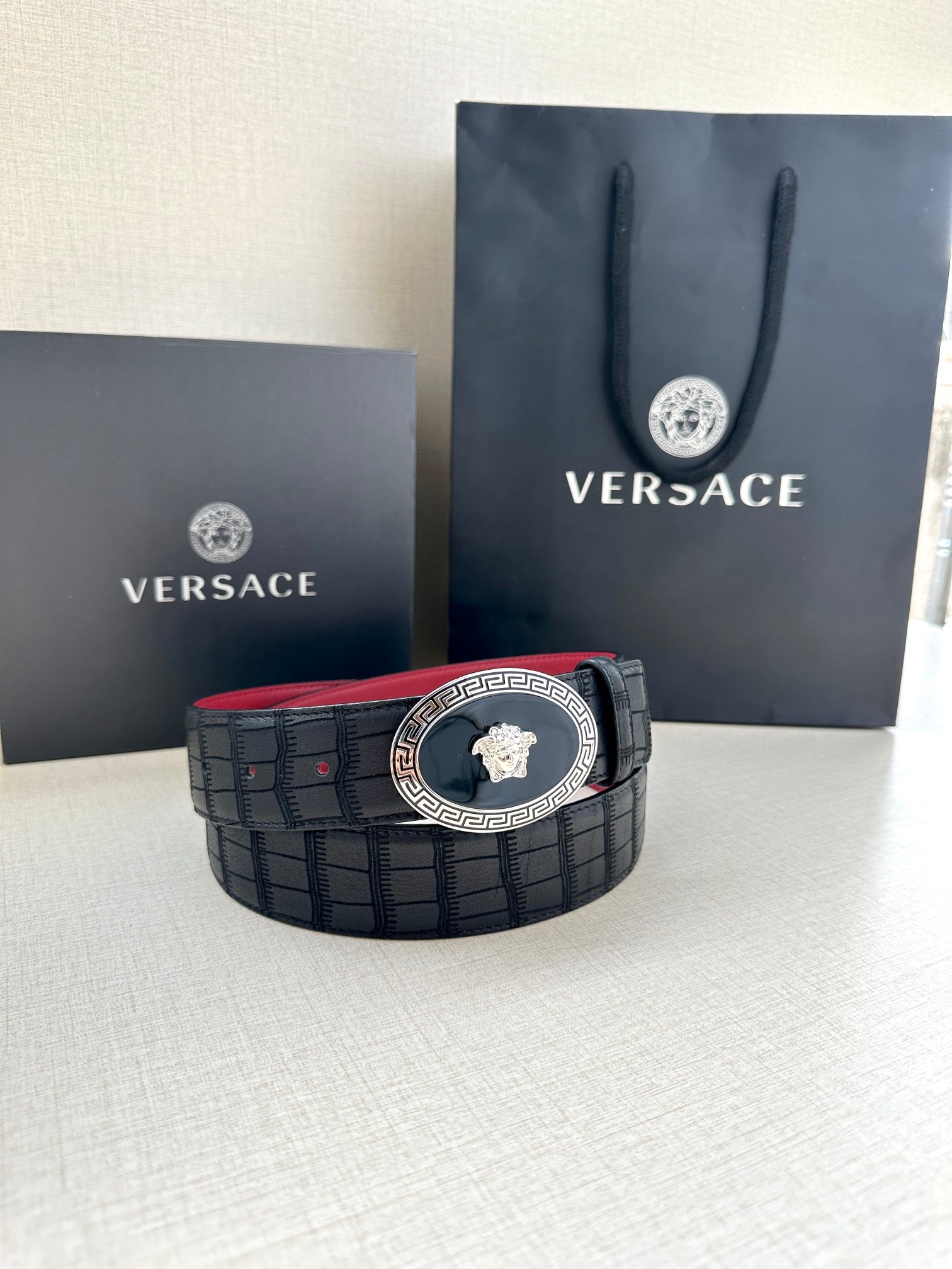 Versace belt on display: black textured strap with round gold medallion buckle