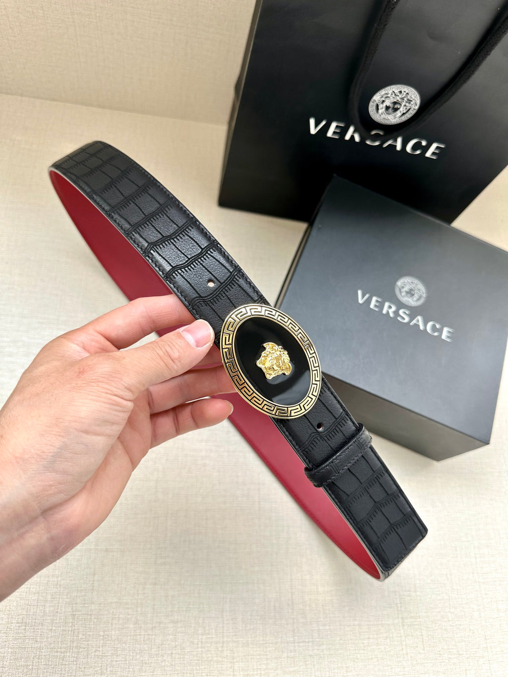 Versace belt with black textured pattern and gold medallion buckle, red underside