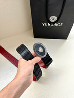 Versace belt close-up of black textured strap and round medallion buckle, red edge