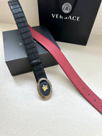 Versace belt laid flat: black textured strap, red interior edge, round gold medallion buckle
