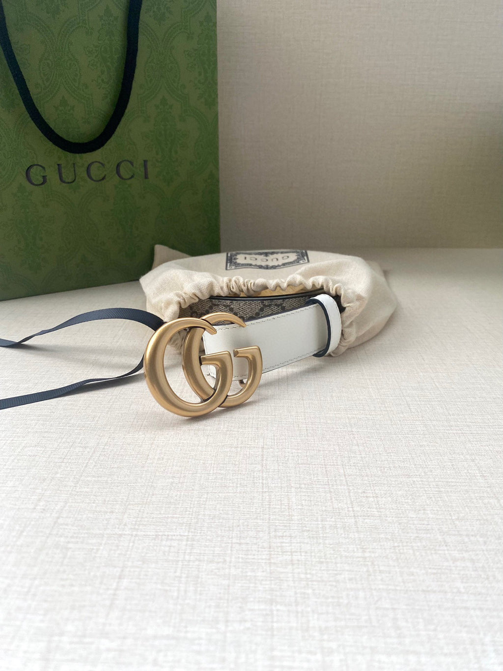 White leather belt with gold-tone double G buckle, shown on accessories