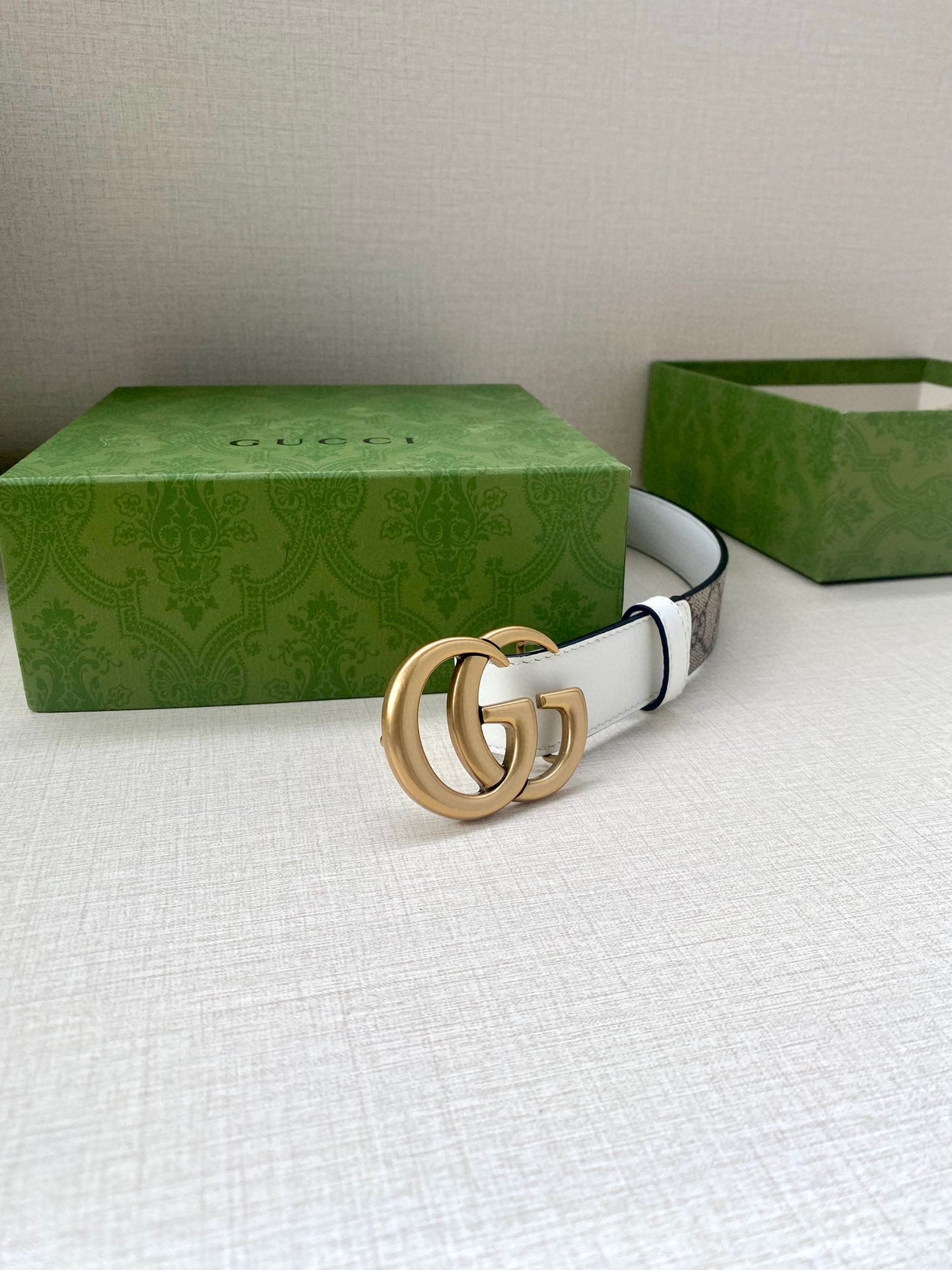 White leather belt with gold-tone double G buckle and no visible strap end