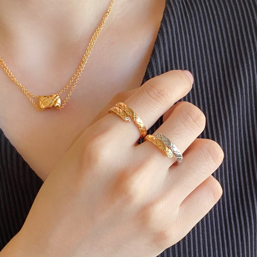 Gold-tone ring with lattice design and matching necklace on a hand