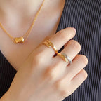Gold-tone ring with lattice design and matching necklace on a hand