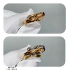 Two rings on glove: gold-tone and silver-tone bands with crisscross lattice texture