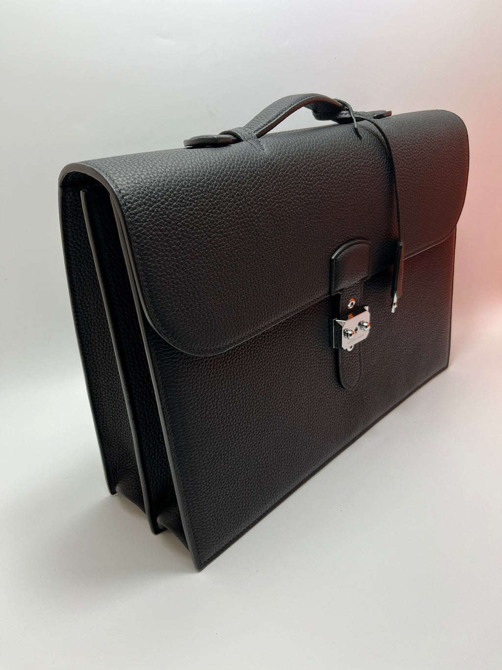 Dark gray leather satchel bag with side view, top handle, and front clasp