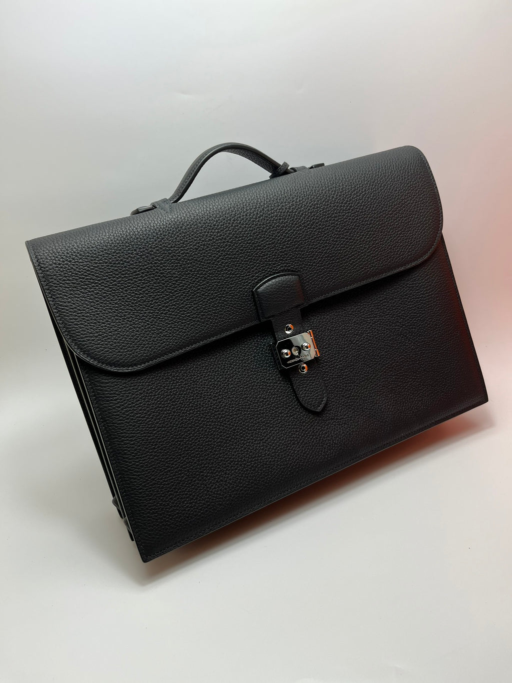 Dark gray leather satchel bag with front flap, top handle, and metal clasp