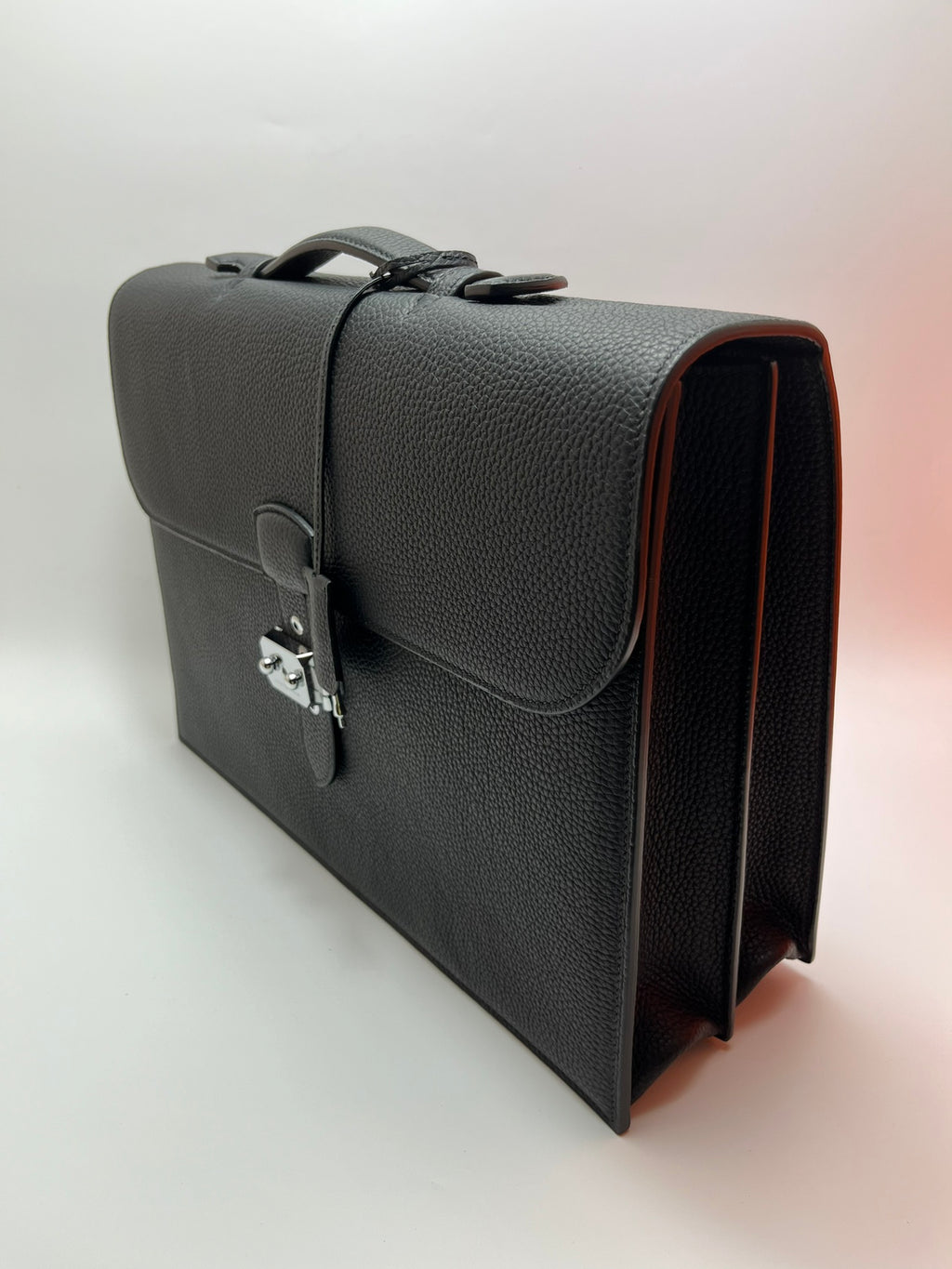 Dark gray leather satchel bag angled view with front flap and side strap