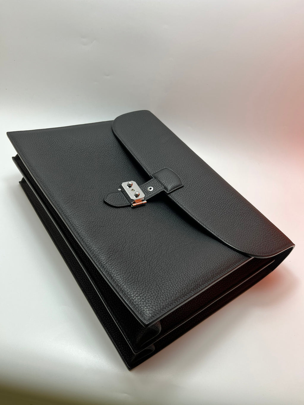 Dark gray leather satchel bag laid flat with front flap and metal lock