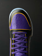 Low-top basketball shoe front side, purple perforated panel, purple laces, yellow edge trim.