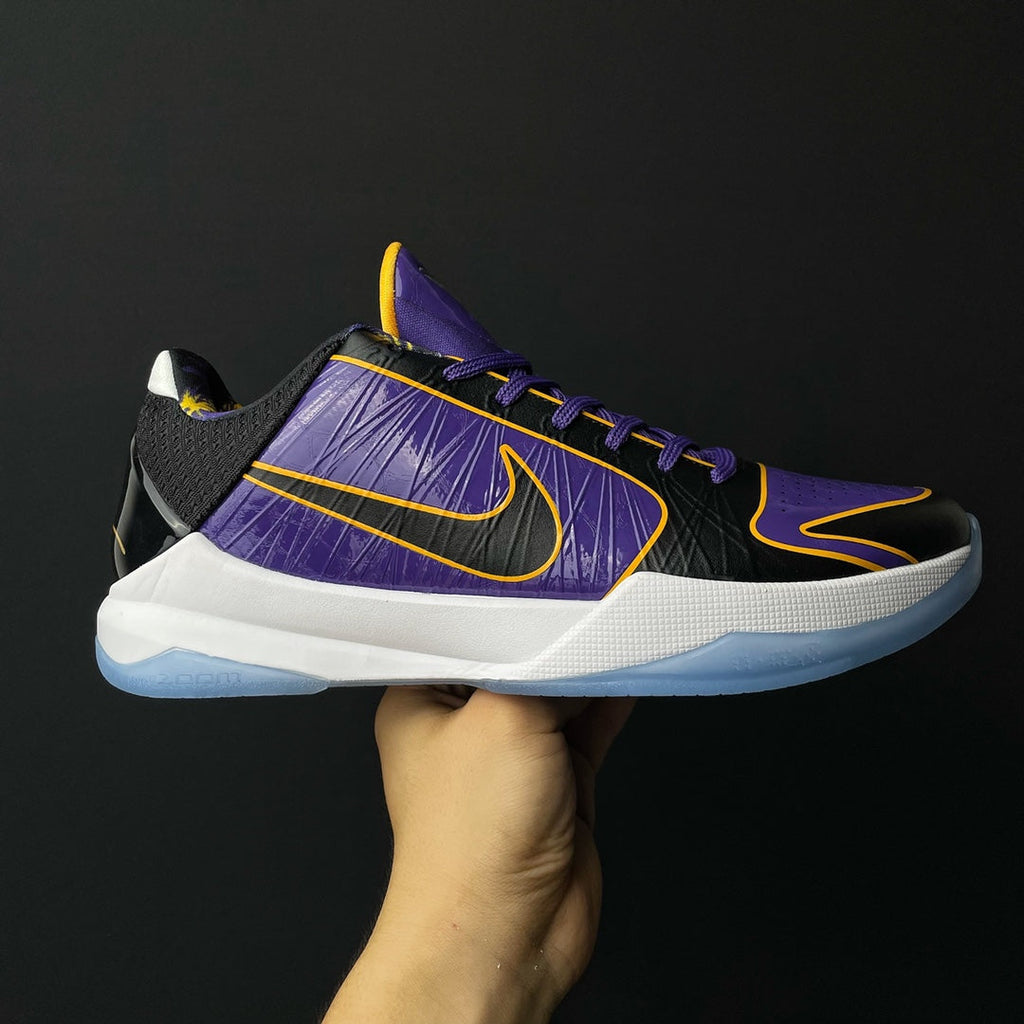 Low-top basketball shoe, purple knit upper with black panels, yellow swoosh, white midsole.
