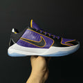 Low-top basketball shoe, purple knit upper with black panels, yellow swoosh, white midsole.