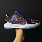 Low-top basketball shoe, purple knit upper with black panels, yellow swoosh, white midsole.