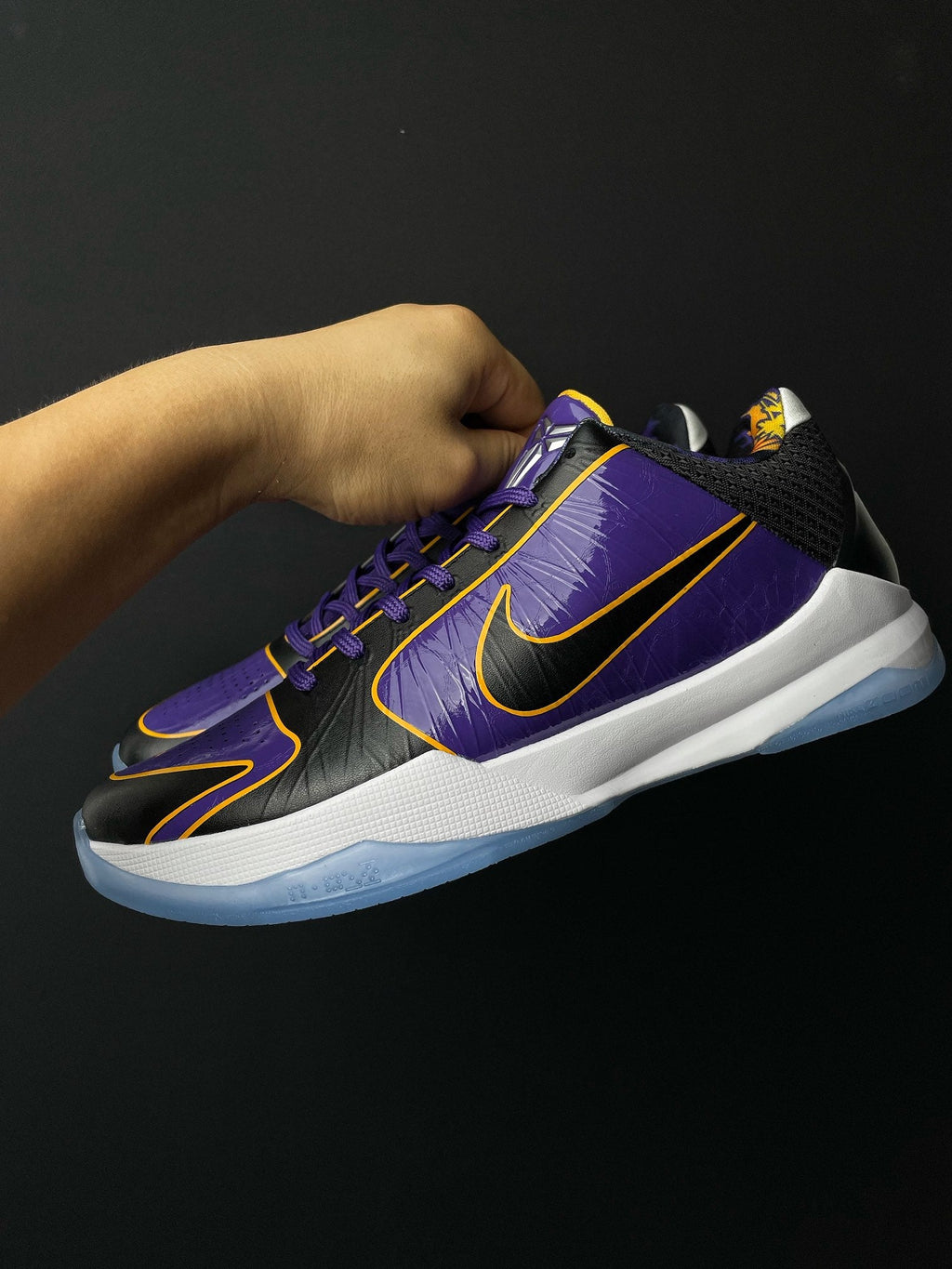 Low-top basketball shoe, purple upper with black toe, yellow trim, lace-up design.