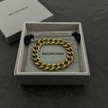 Balenciaga gold-tone chain bracelet with BALENCIAGA logo plate and black tassel ends