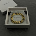 Balenciaga gold-tone chain bracelet with BALENCIAGA logo plate and black tassel ends