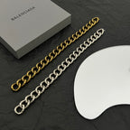 Balenciaga chain bracelet set: gold-tone and silver-tone link bracelets on black surface