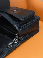 Black quilted leather crossbody bag with flap closure and silver chain strap