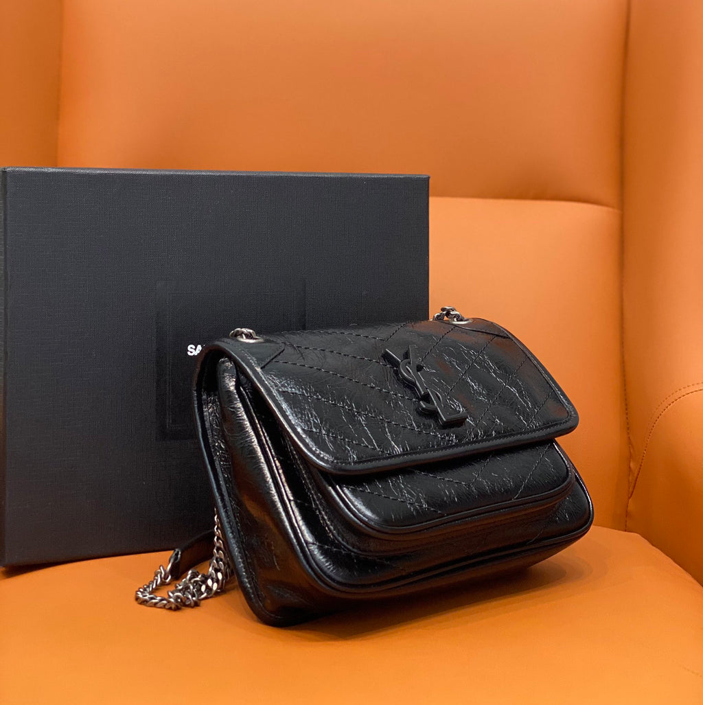 Black quilted leather crossbody bag with flap closure, chain strap, and metal hardware