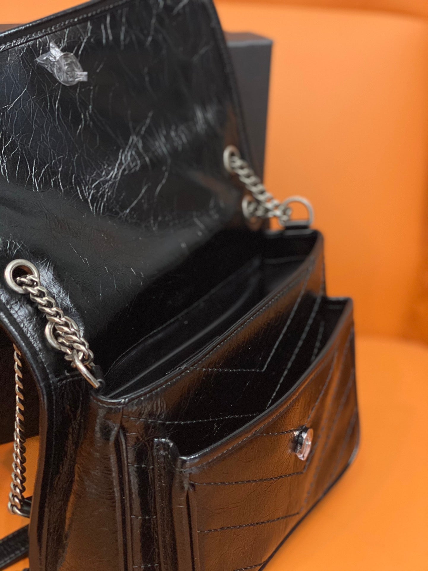 Black leather flap bag close-up showing interior lining and chain strap hardware