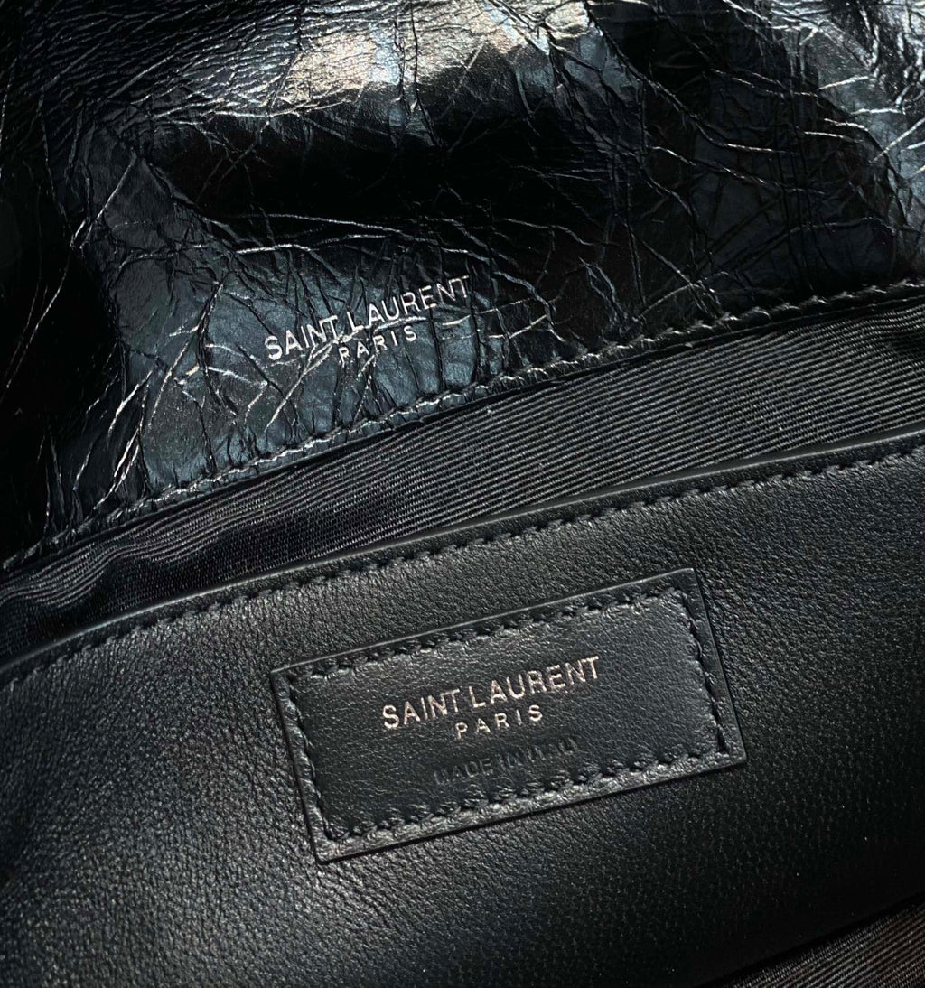 Black leather bag close-up of "SAINT LAURENT PARIS" logo label