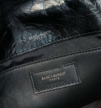 Black leather bag close-up of "SAINT LAURENT PARIS" logo label