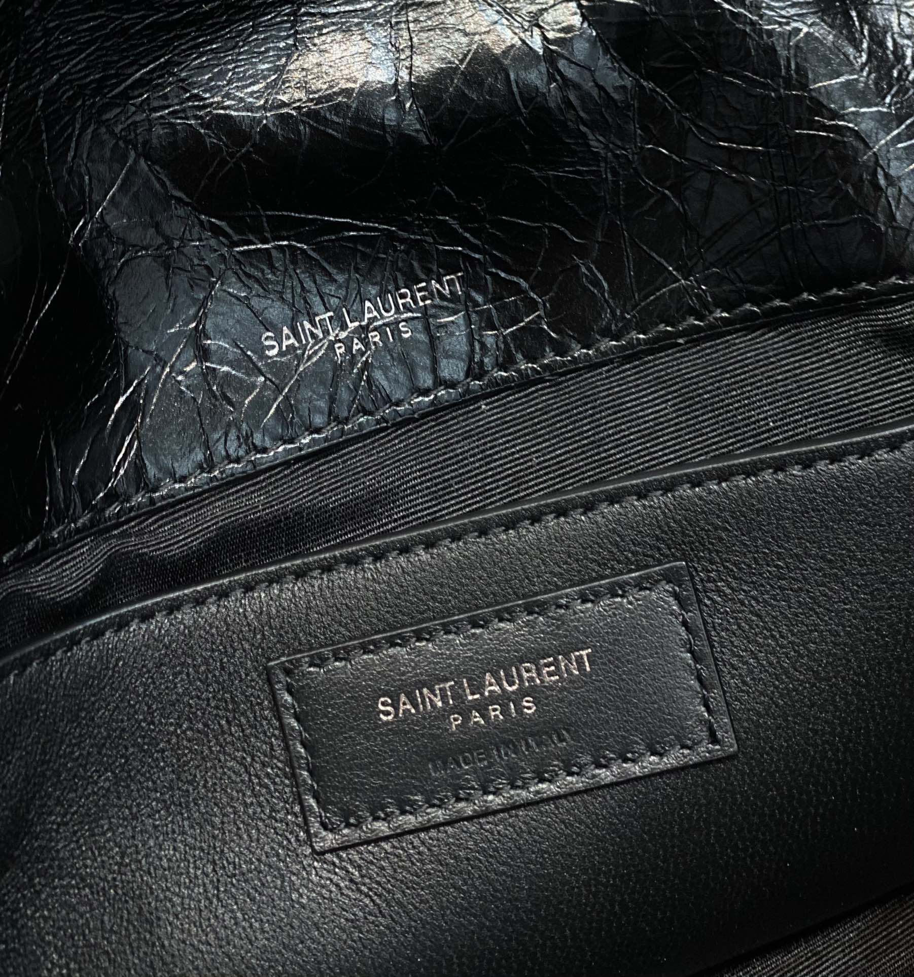 Black leather bag close-up of "SAINT LAURENT PARIS" logo label