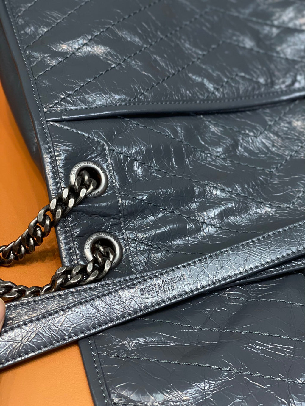 Saint Laurent leather crossbody bag detail with chain ring, stitching, and zip trim
