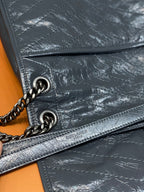 Saint Laurent leather crossbody bag detail with chain ring, stitching, and zip trim