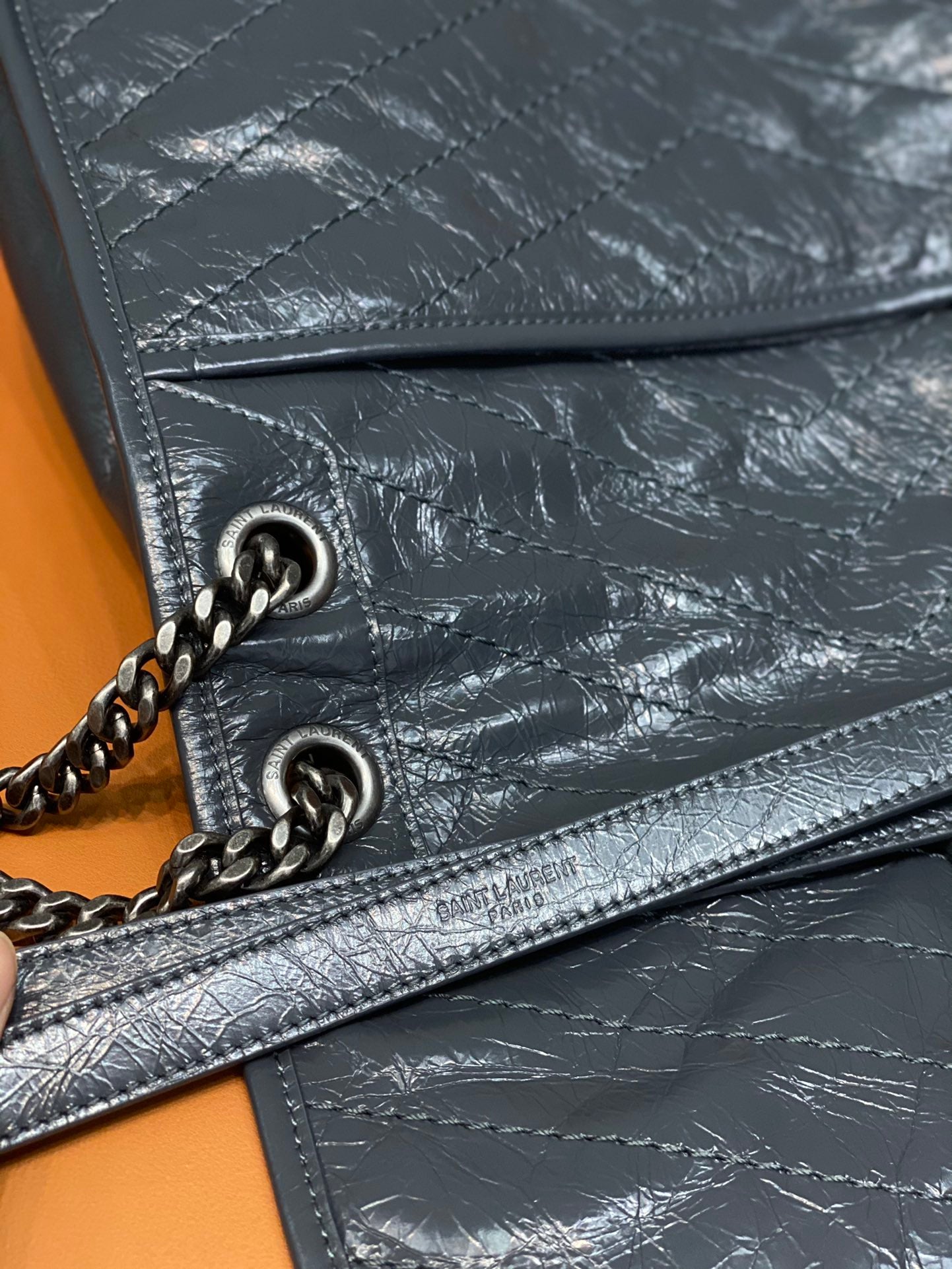 Saint Laurent leather crossbody bag detail with chain ring, stitching, and zip trim