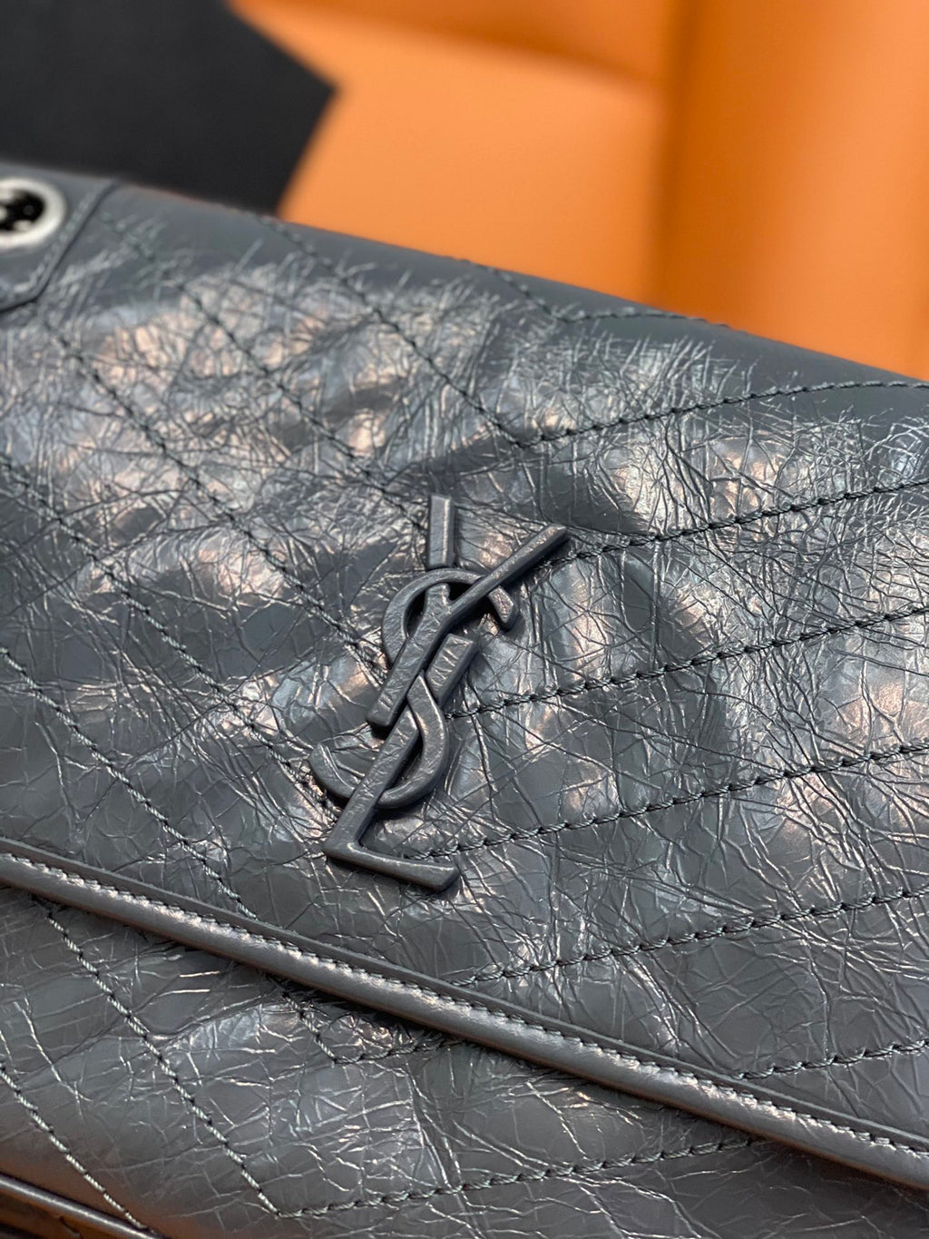 Saint Laurent YSL logo emblem on quilted dark blue leather flap with snap hardware