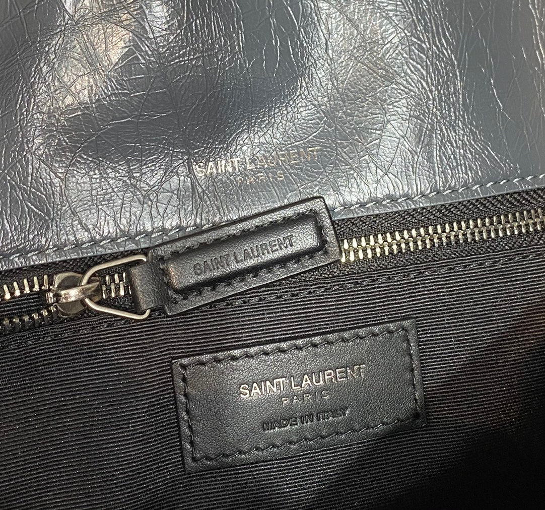 Saint Laurent zip pull and brand label on textured dark blue leather bag