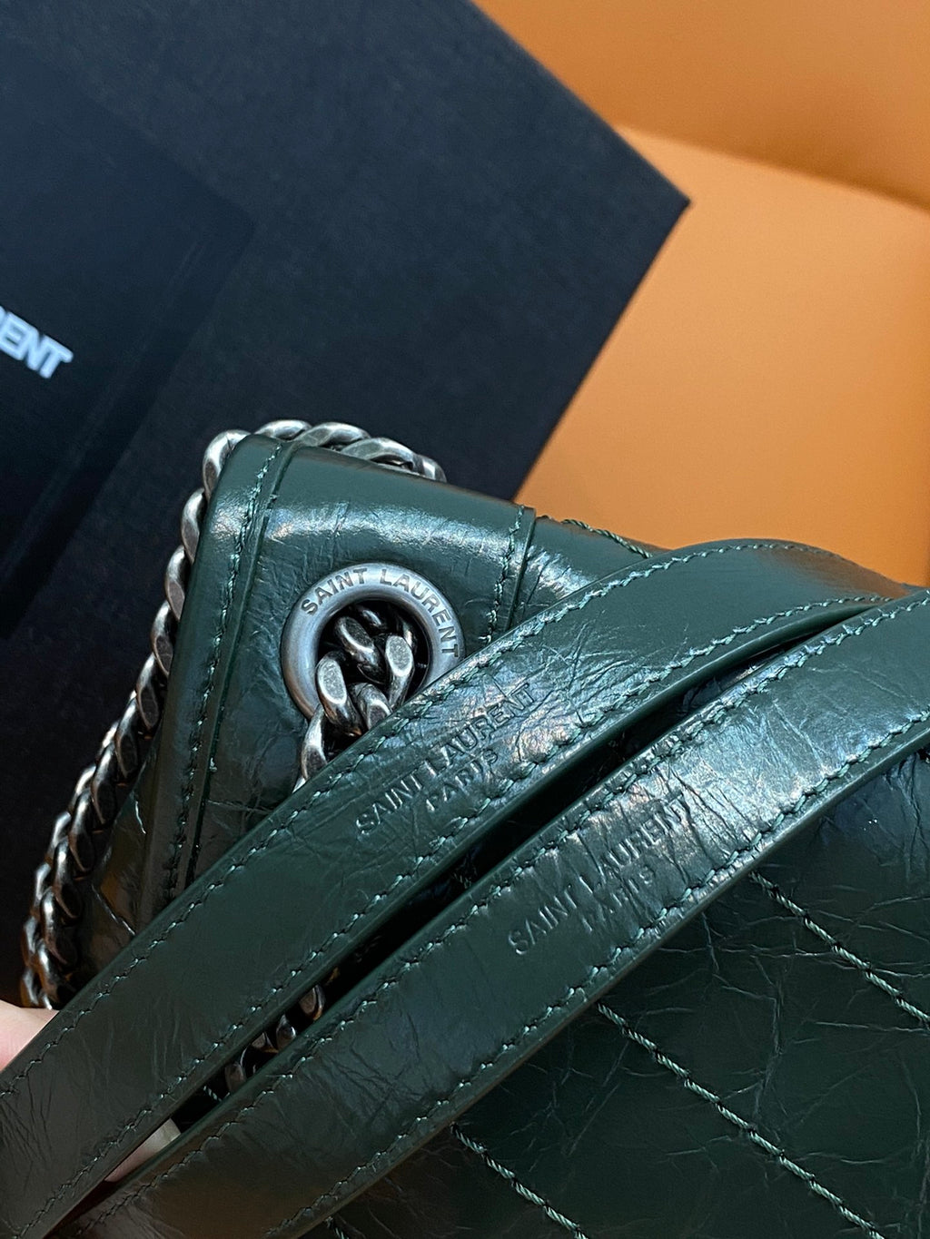 Dark green leather bag with chain strap and embossed logo on flap