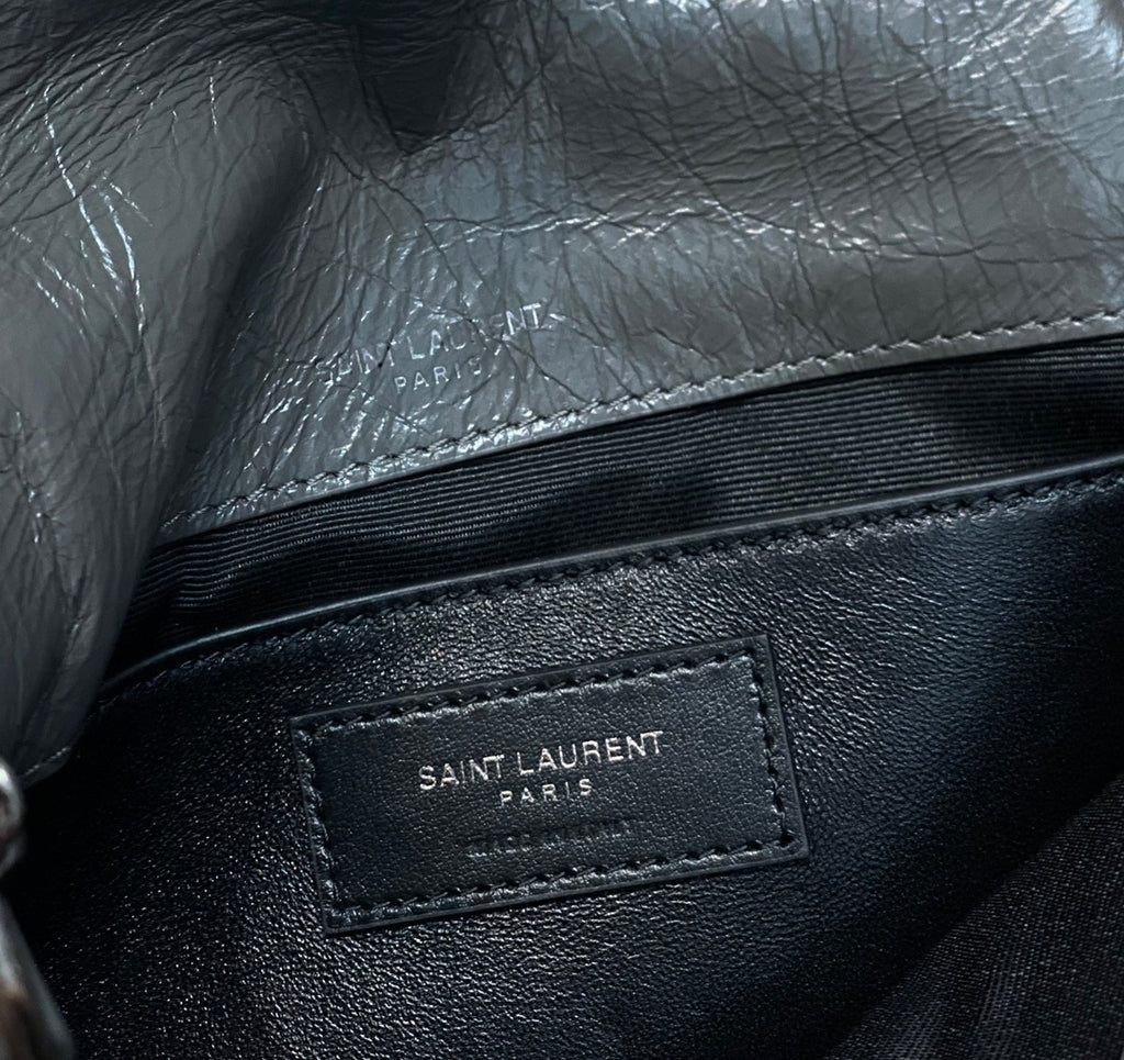 Black leather bag with interior brand label patch reading “SAINT LAURENT PARIS”