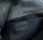 Black leather bag with interior brand label patch reading “SAINT LAURENT PARIS”
